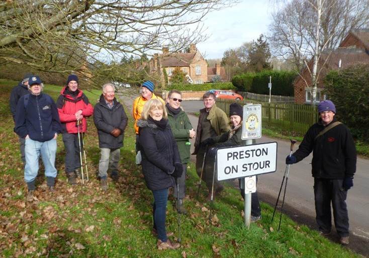 A group of people standing around a sign

Description automatically generated with medium confidence