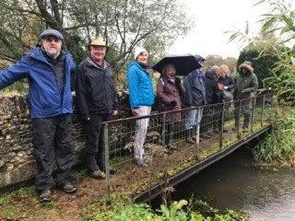 A group of people standing on a bridge over a stream

Description automatically generated with medium confidence