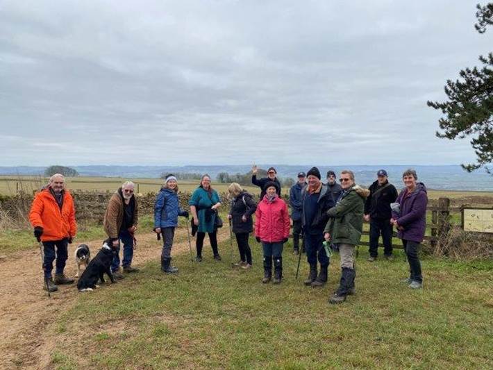 A group of people standing on a hill with a dog

Description automatically generated with medium confidence